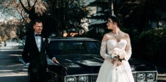 Para młoda w retro stylu pozuje przy zabytkowym aucie w słoneczny dzień