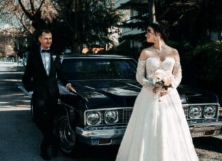 Para młoda w retro stylu pozuje przy zabytkowym aucie w słoneczny dzień