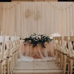 Elegancka aranżacja sali weselnej z kwiatami i stylowymi krzesłami