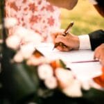 Para podpisuje dokument ślubny podczas plenerowej ceremonii